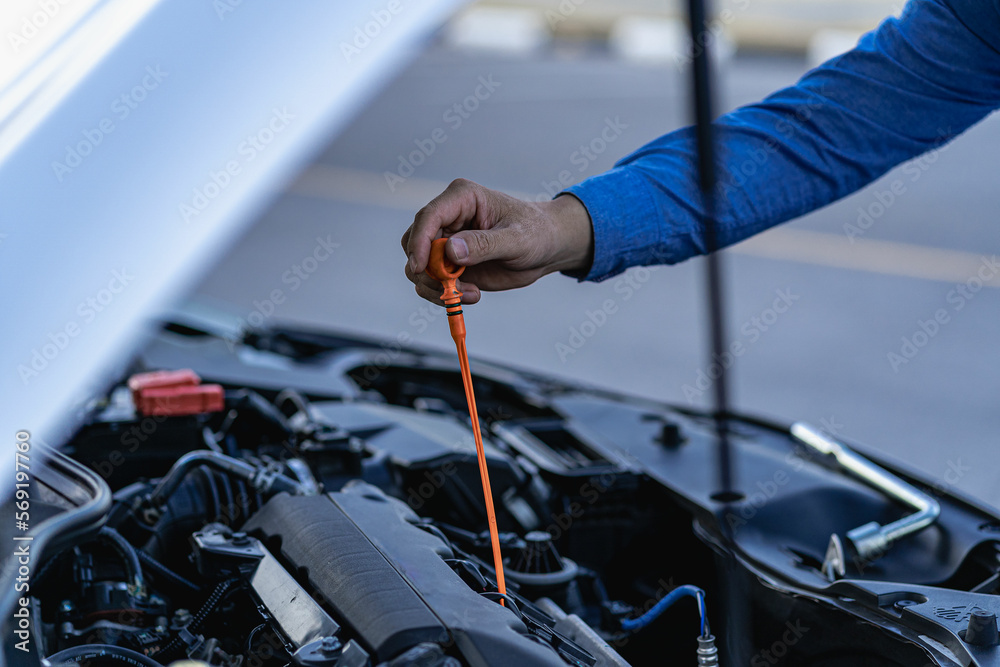 Young man checking and maintaining the quality of engine oil in his car Car repair and maintenance, oil change before long journey, car mechanic concept Young man checking and maintaining the quality of engine oil in his car Car repair and maintenance, oil change before long journey, car mechanic concept