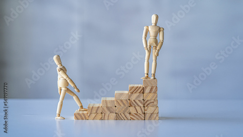 Wooden block and wooden puppet walking up stairs with puppet standing waiting business success concept.