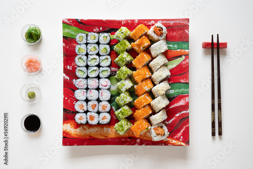Maki sushi on a dish with chop sticks, soya, fresh ginger and wasabi