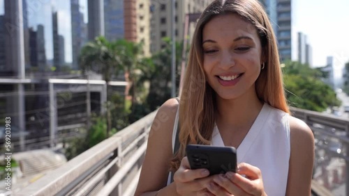 Beautiful Brazilian woman messaging with smartphone in the modern sustainable metropolis of Sao Paulo, Brazil