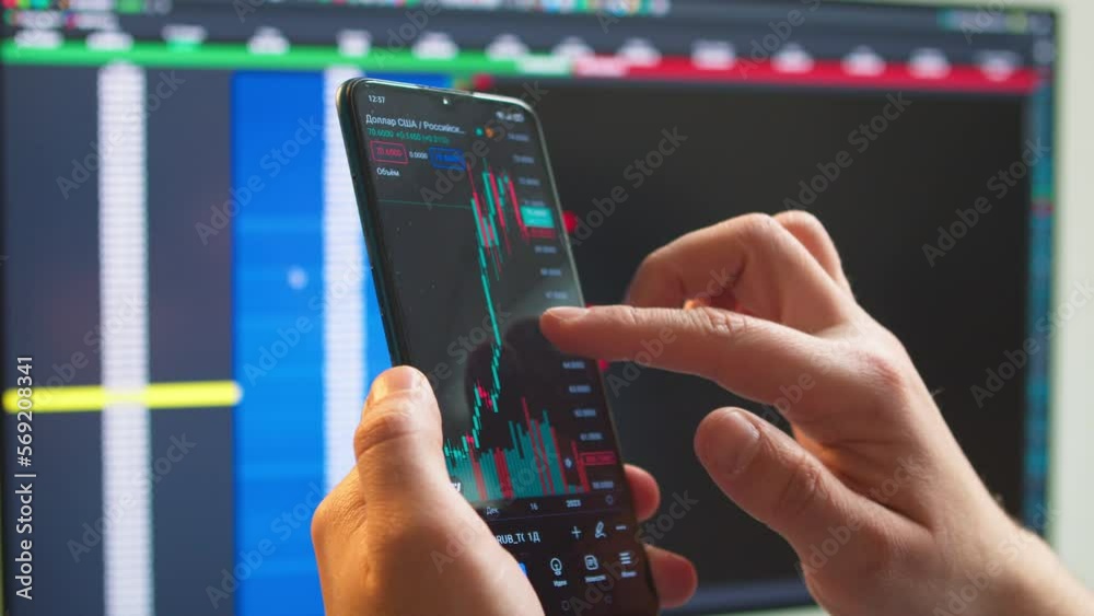 Close-up - a male broker financial analyst checks a bitcoin price chart on a digital exchange on a smartphone, predicts the future movement of the cryptocurrency price. Close-up - a male broker financial analyst checks a bitcoin price chart on a digital exchange on a smartphone, predicts the future movement of the cryptocurrency price.