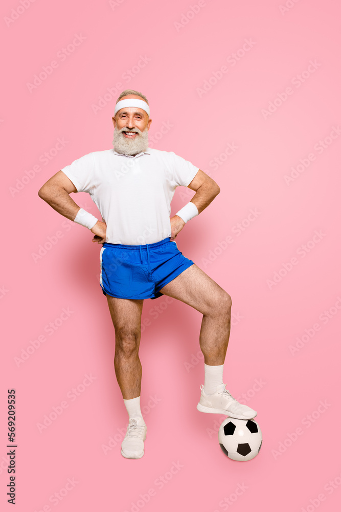 Full length of modern cool funny competetive pensioner, leader, champion with his foot on a ball. Bodycare, healthcare, weight loss, pride, strength, leadership, motivation, authority, gym