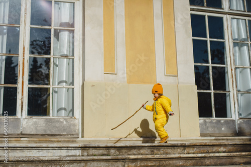 A child in a yellow jumpsuit and hat walks in a park with a fountain at Villa Durazzo in Genoa, Italy © katya