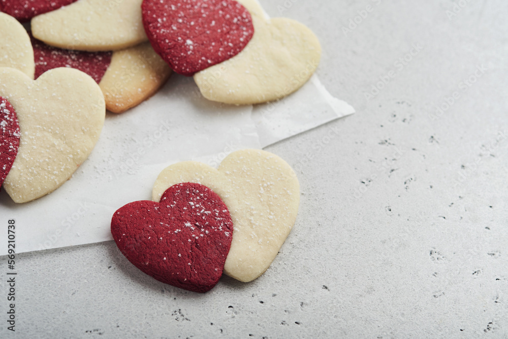 Obraz premium Valentines day cookies. Shortbread cookies inside sweet red heart with chocolate glaze on pink plate on grey background. Mothers day. Womans day. Sweet holidays baking. Valentines day card. Top view.