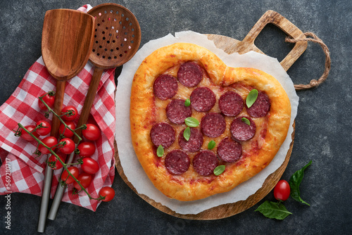 Valentines day heart shaped pizza with mozzarella, pepperoni and basil, wine bottle, two wineglass, gift box on black background. Idea for romantic dinner Valentines day. Top view. Mock up.