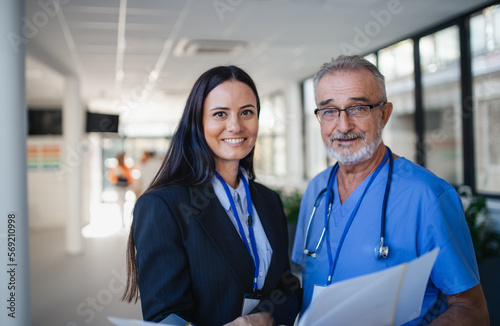 Portrait of elderly doctor and business woman at hospital corridor. photo