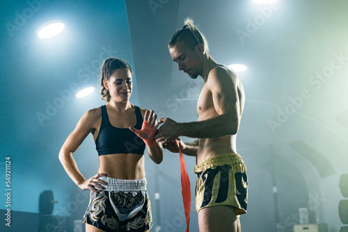 Man preparing bandages for woman Muay Thai boxer getting ready for fight.