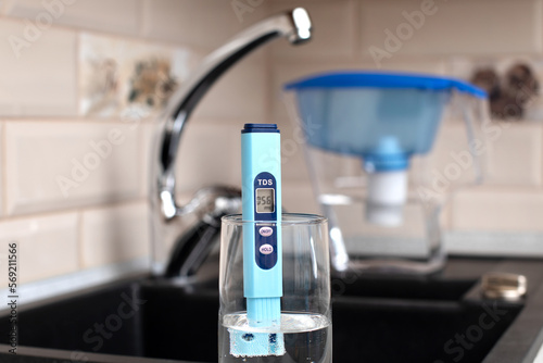 Tds meter for measuring water hardness is in the kitchen next to the sink, blue filter jug for water