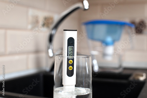 Tds meter for measuring water hardness is in the kitchen next to the sink, blue filter jug for water