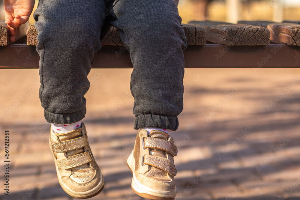 Little child sitting on a bench legs only Little child sitting on a bench legs only