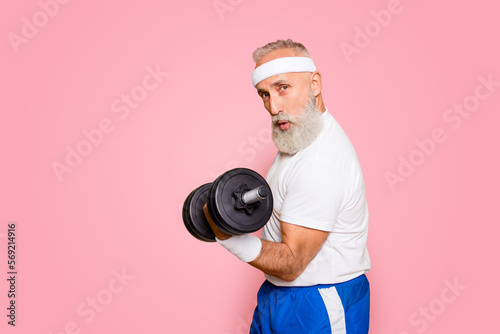 Cool playful flirty naughty strong grandpa with confident grimace exercising holding equipment up, lifts it with strength and power. Body care, fitness, body building, hobby, weight loss lifestyle