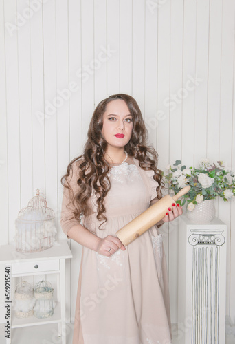 Young beautiful woman pregnant wearing retro style dress holding rolling pin