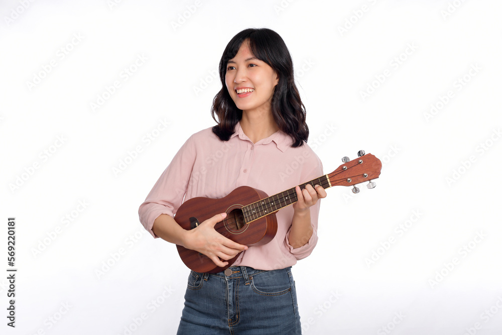 Happy young asian woman with casual clothing playing ukulele isolated on white background Happy young asian woman with casual clothing playing ukulele isolated on white background