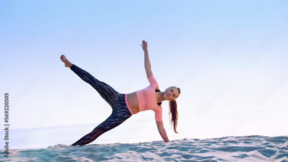 Healthy, young beautiful woman doing exercises for oblique abdominal press muscles,, on the beach, at sunrise, Makes exercises for balance and coordination, deep muscle tone.