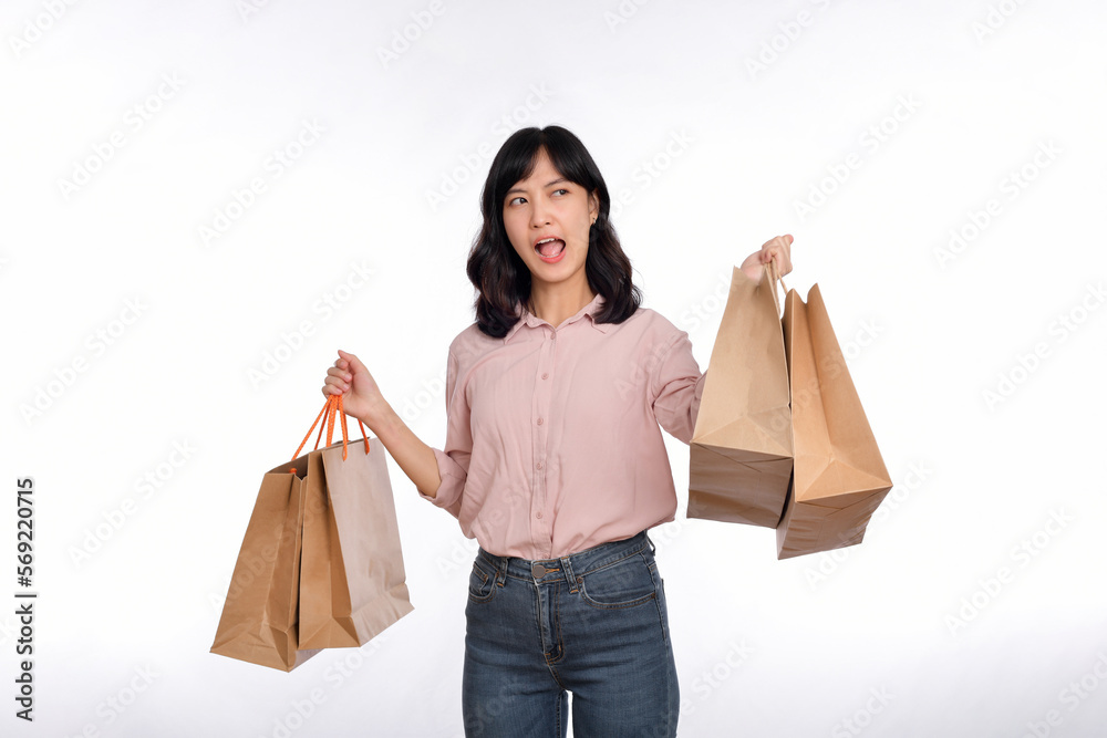 Young happy asian woman with casual shirt and denim jeans holding shopping paper bag isolated on white background Young happy asian woman with casual shirt and denim jeans holding shopping paper bag isolated on white background
