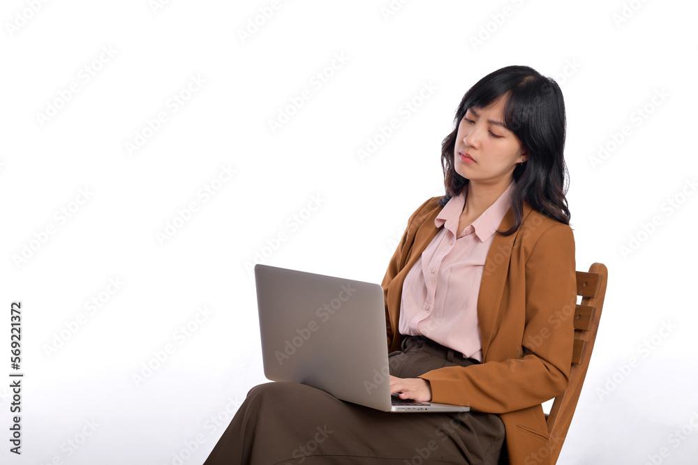 Upset young business asian woman. While her using laptop sitting on wooden chair isolate on white background Upset young business asian woman. While her using laptop sitting on wooden chair isolate on white background