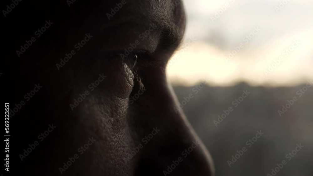 Dramatic isolated portrait of a man who opens his eyes and looks out the window with sad pensive look. Closeup of male eye. Slow motion. A man is worried and thinking while looking into the distance.