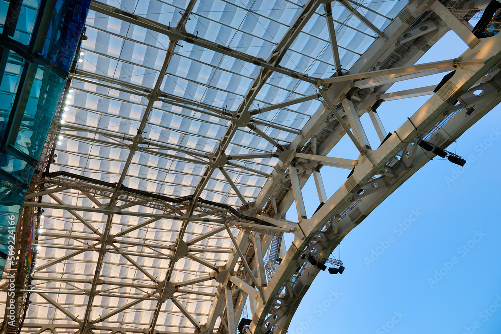 Modern steel structure of the stadium roof. In the indoor arena of the stadium there are bright LED lights on the roof on a metal structure. 