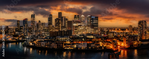 Canary Wharf and London city skyline at dusk with setting sun and street lighting looking at finance and business district of the city of London, united kingdom. Aerial view with dramatic sunset photo