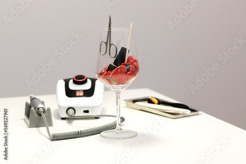 St Valentine's Day concept for manicure, pedicure service, spa salon. Wine glass filled with red hearts, nail polish,oil,professional manicure machine Love, affection International Women Day. Vertical photo