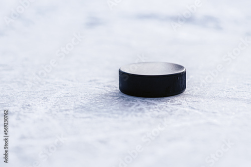 black hockey puck lies on ice at stadium