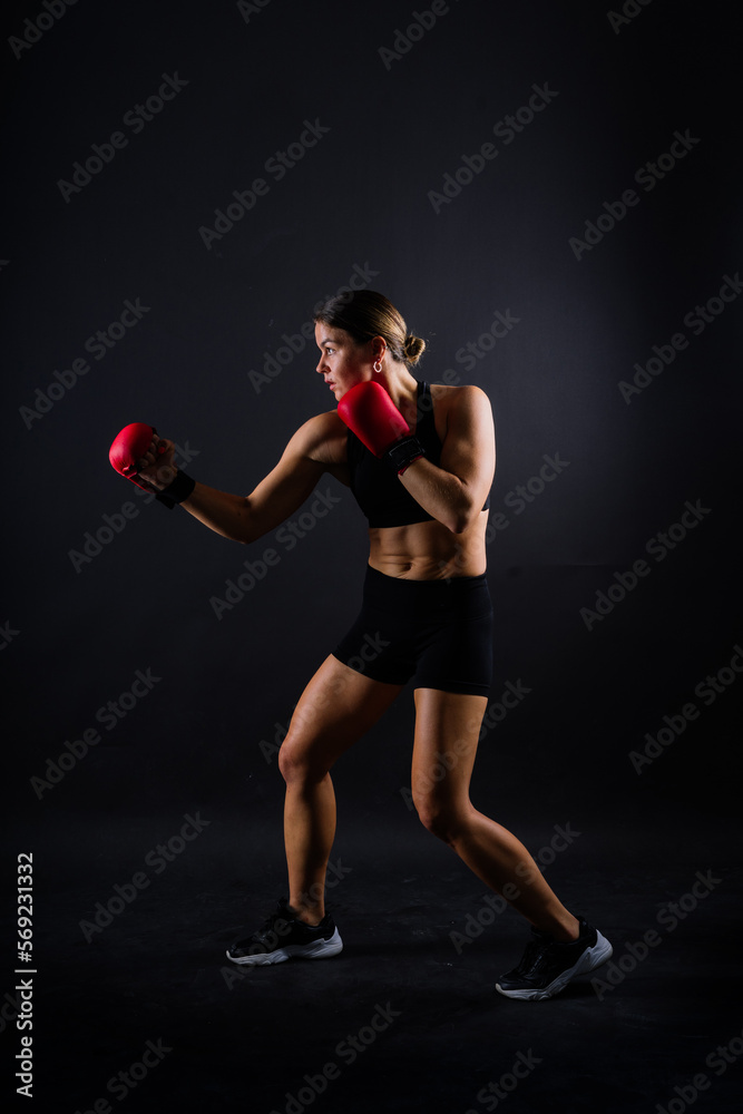 Strong sportswoman in boxing gloves prepared high kick. Isolated on white, red, yellow background