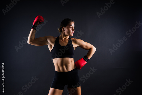 Strong sportswoman in boxing gloves prepared high kick. Isolated on white, red, yellow background