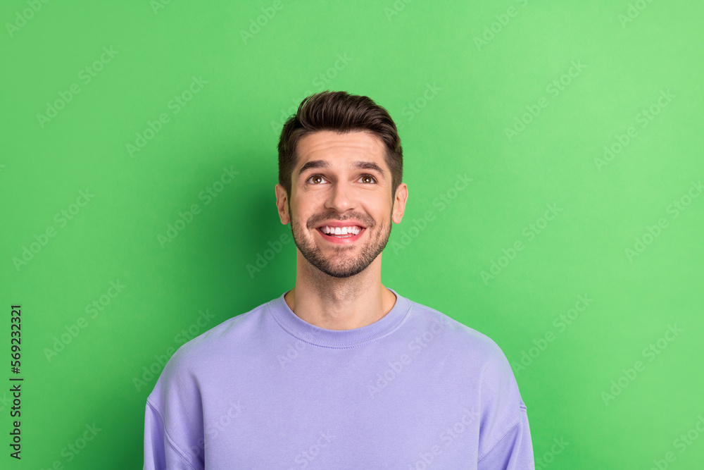 Photo of funny thoughtful young guy dressed violet clothes looking up empty space isolated green color background Photo of funny thoughtful young guy dressed violet clothes looking up empty space isolated green color background