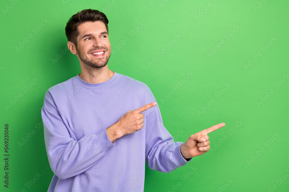 Photo of positive nice person beaming smile look indicate fingers empty space isolated on green color background Photo of positive nice person beaming smile look indicate fingers empty space isolated on green color background