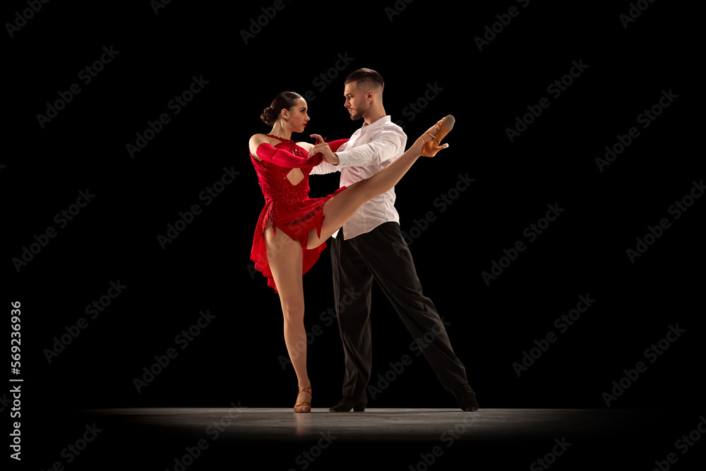 Deep look. Handsome young man and a beautiful woman dancing tango, ballroom over black background. Concept of hobby, lifestyle, action, beauty of movements, emotions, fashion, art