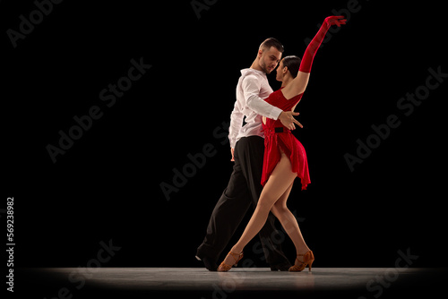 Fényképezés Passionate attractive young man and woman, professional ballroom dancers dancing tango over black background