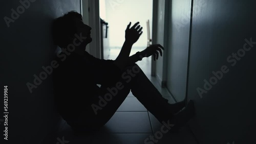 One anxious depressed man in despair sitting at home in the dark. Person suffering from mental illness alone in corridor feeling shame and regret photo