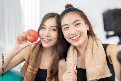 Beautiful Asian woman taking selfie with friend while exercising at home.