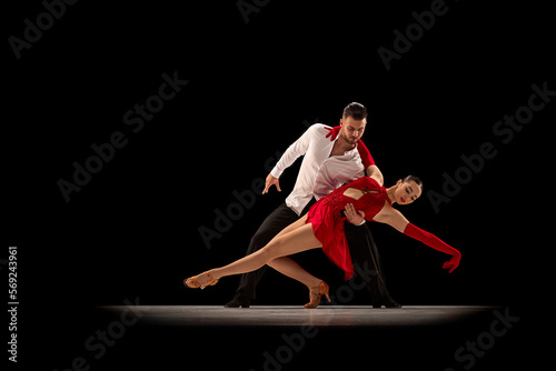 Beautiful, talented, attractive young man and woman, professional dancers performing, dancing tango over black background. Concept of lifestyle, action, beauty of movements, emotions, fashion, art © master1305