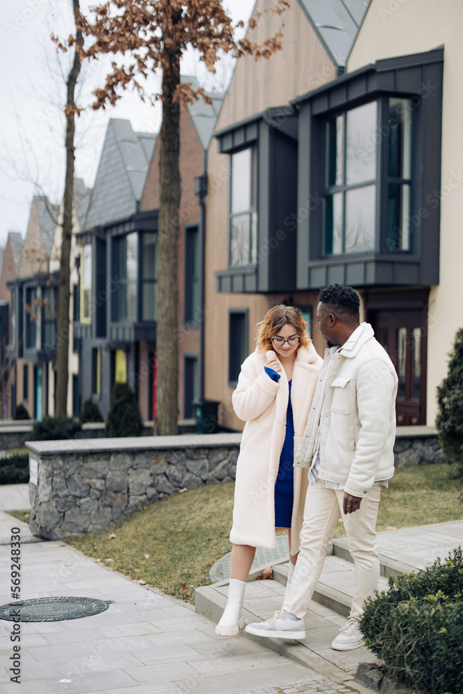 Young interracial couple holds each other hand and walks on street. Young interracial couple holds each other hand and walks on street.