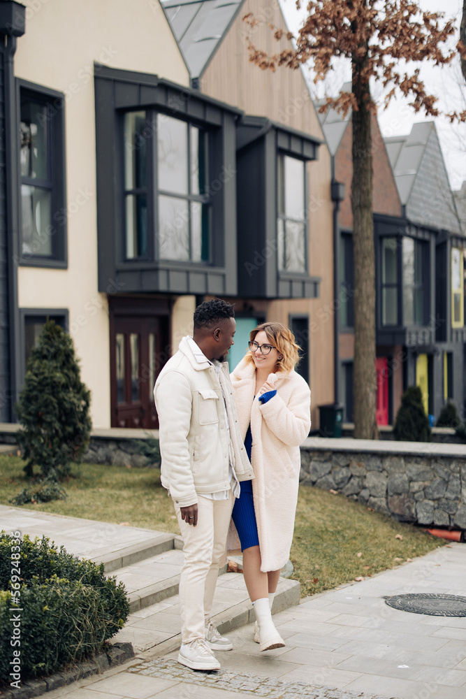 Young interracial couple holds each other hand and walks on street. Young interracial couple holds each other hand and walks on street.