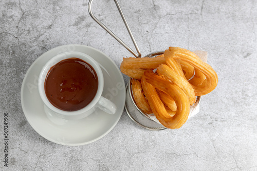 Churros basket with cup of chocolate seen from above on gray stone background, typical Spanish breakfast photo