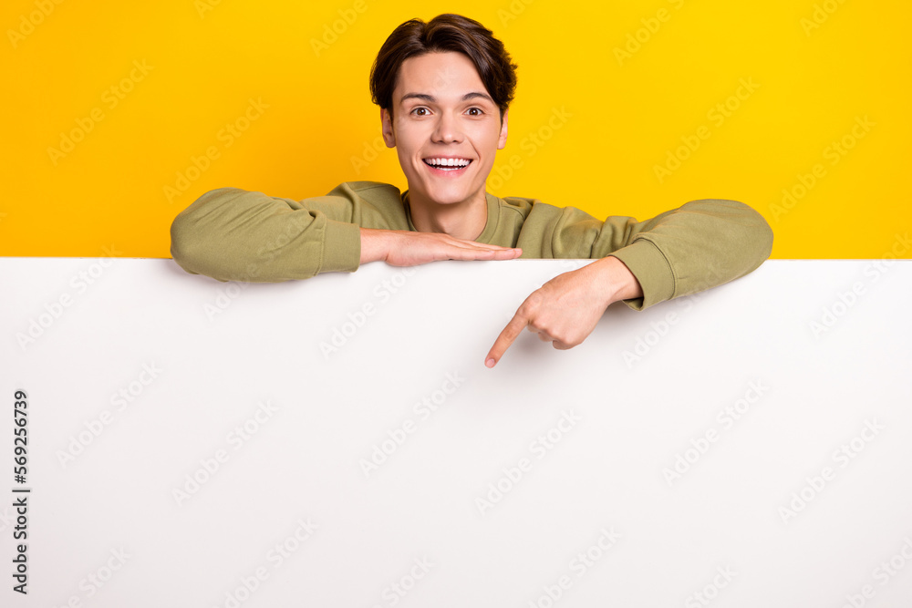 Photo of excited positive man wear trendy clothes arm direct empty space special offer proposition isolated on yellow color background Photo of excited positive man wear trendy clothes arm direct empty space special offer proposition isolated on yellow color background