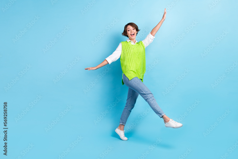 Full size portrait of pretty overjoyed girl dancing walk empty space isolated on blue color background
