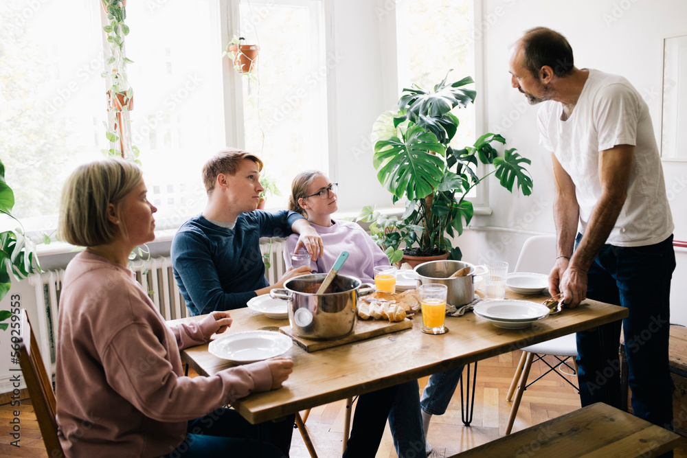 Family talking with dad standing near table at home Family talking with dad standing near table at home