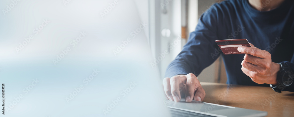 Man hand holding credit card and using laptop at home, Businessman or entrepreneur working, Online shopping, e-commerce, internet banking, spending money concept. Man hand holding credit card and using laptop at home, Businessman or entrepreneur working, Online shopping, e-commerce, internet banking, spending money concept.