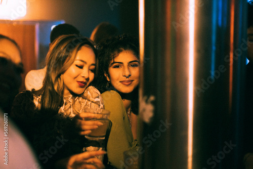 Happy female friends dancing while enjoying in club at night
