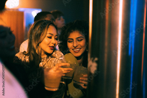 Cheerful young friends with drinks enjoying in club on weekend