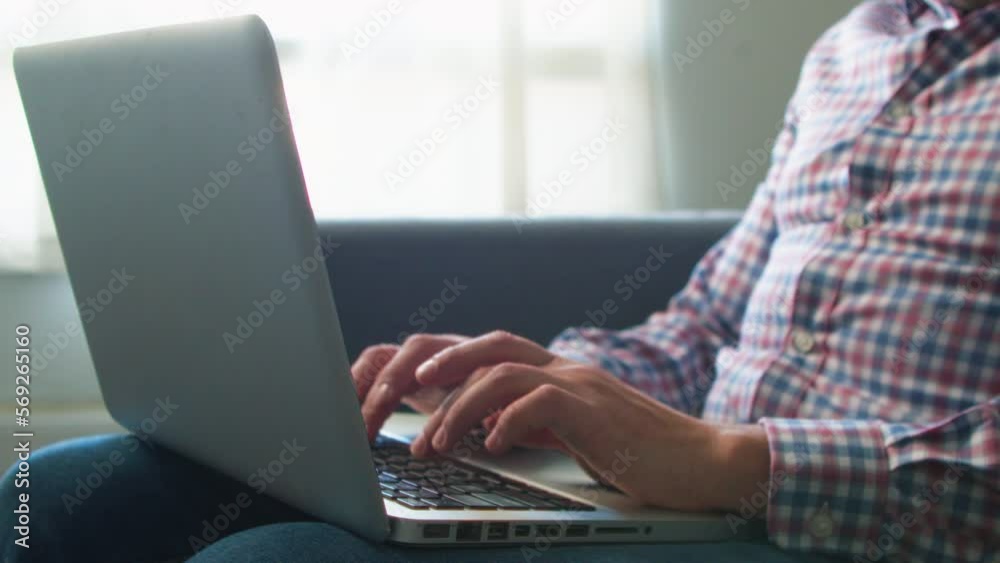 Male freelancer typing with hands on laptop keyboard, sitting on sofa in room working from home, businessman, hipster, student, vocational study, work with pc software technology concept, closeup 