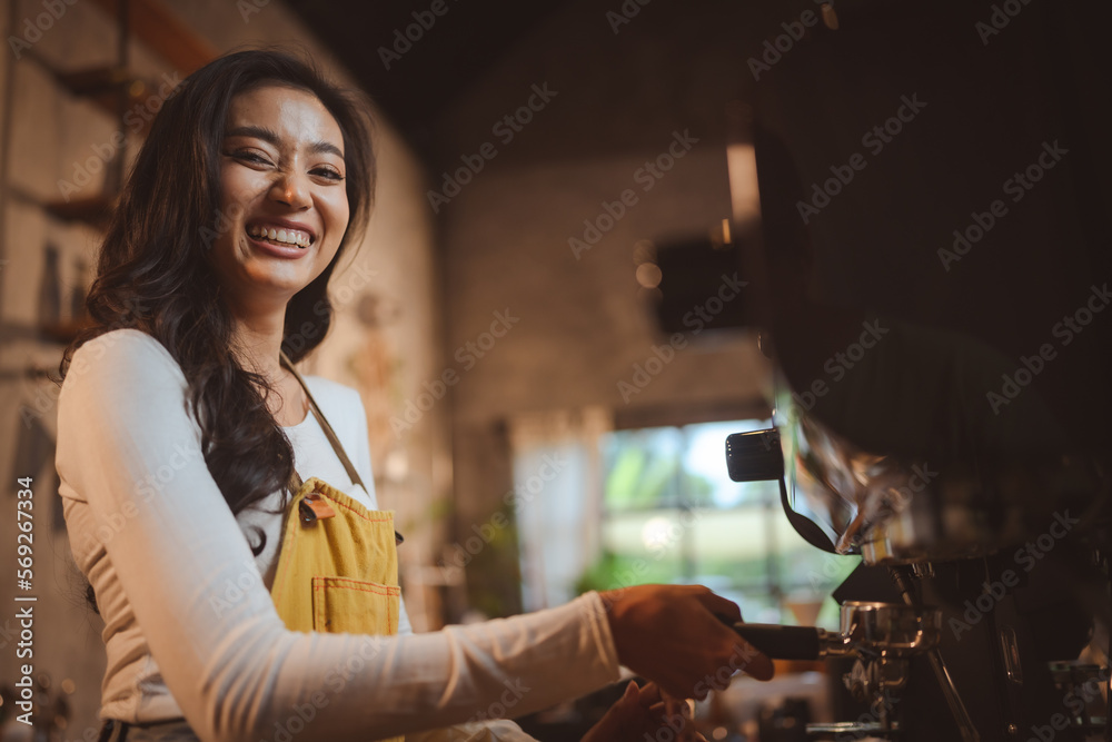 Smiling young female barista with male colleague in apron preparing coffee while holding filter and equipment while preparing beverage for customer in modern cafe