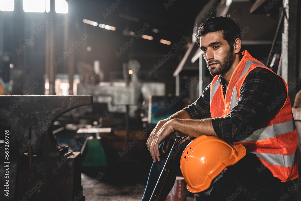 Young Asian male worker wearing safety vest jacket and hard helmet with protective glasses working in coal mine factory and warehouse using spade to move pieces of coal Young Asian male worker wearing safety vest jacket and hard helmet with protective glasses working in coal mine factory and warehouse using spade to move pieces of coal