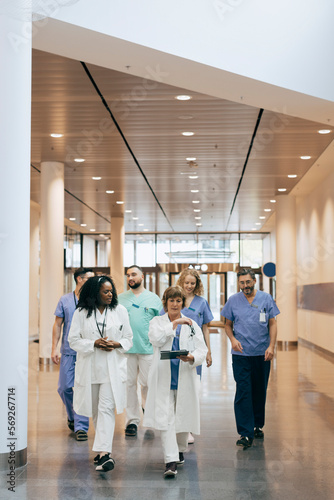Male and female healthcare workers discussing while walking in hospital