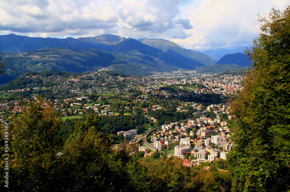 Panoramic view of the mountains  and a city at their feet from Mount San Salvatore in the city of Lugano, in southern Switzerland	