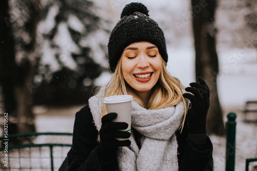 Young woman in warm clothes enjoying in snow with takeaway coffee cup © BGStock72