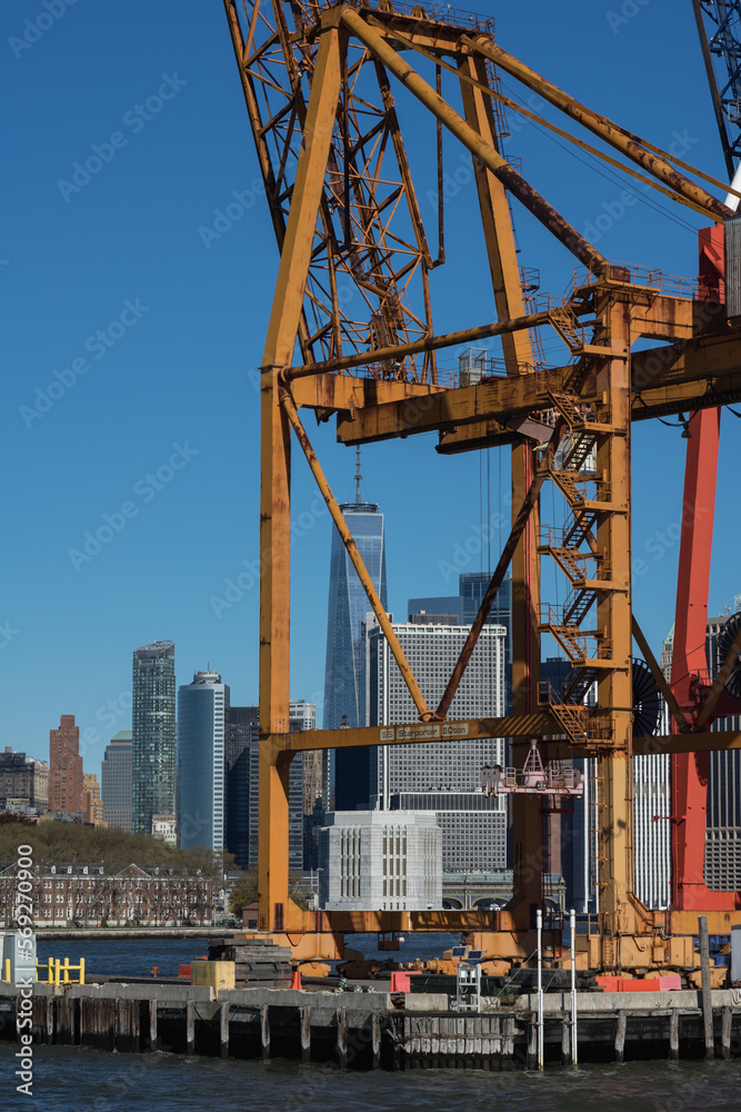 Gelber Kran an Hafen mit Skyline von New York im Hintergrund.